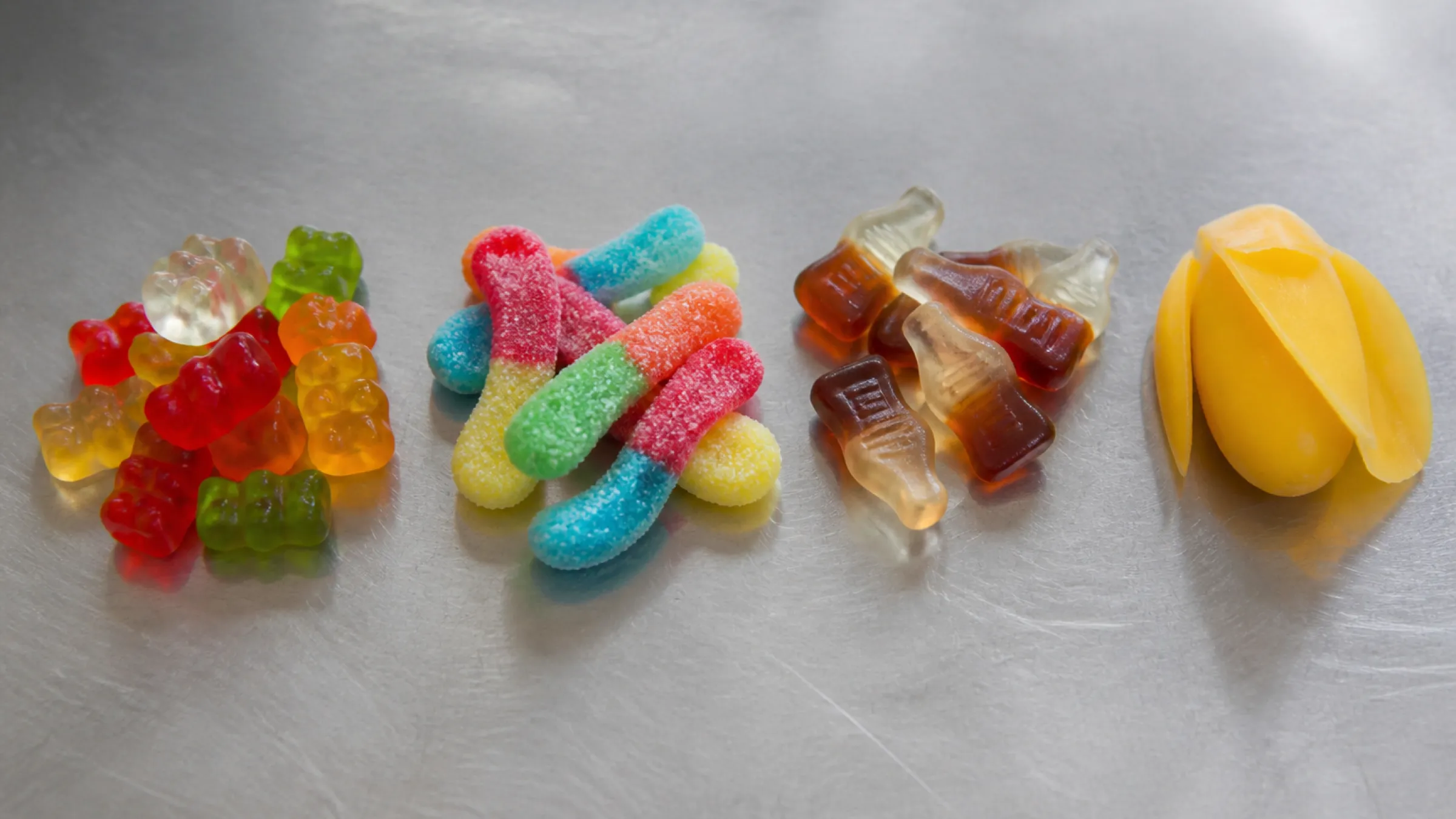 Best-selling gummy candy formats side by side: bears, sour worms, cola bottles and a peelable mango gummy
