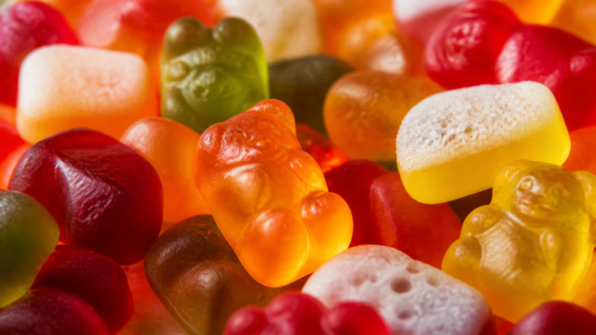 Close-up of glossy gelatin gummy candies showing elastic texture and aerated foan varieties